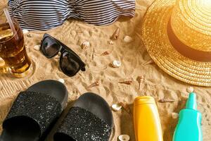 Summer bikini and accessories stylish beach set, Beach bikini summer outfit and sea sand as background, Top View, Concept photo