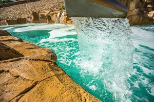 Stream water out of artificial waterfall in outdoor pool photo