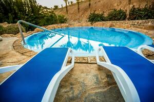 tumbonas y nadando piscina con reflejado palmas en agua foto