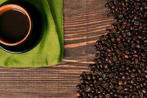 Coffee cup and coffee beans on wooden background. Top view. photo