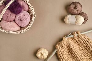 Pink and brown knitting wool and knitting on knitting needles on beige background. Top view. Copy space photo