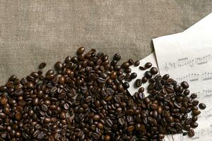 Coffee beans and sheet music on burlap background. photo