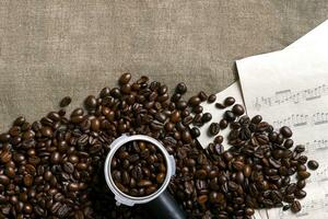 Coffee beans and sheet music on burlap background. photo