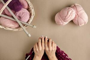 Close-up of female hands knitting wool sweater or plaid lilac color. Top view photo