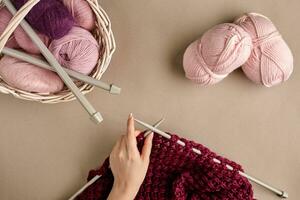 Close-up of female hands knitting wool sweater or plaid lilac color. Top view photo