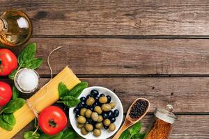 crudo ingredientes para el preparación de italiano pasta, espaguetis, albahaca, Tomates, aceitunas y aceituna petróleo en de madera antecedentes. parte superior vista. Copiar espacio. foto