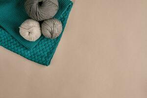 Grey and turquoise knitting wool and knitting needles on beige background. Top view. Copy space photo