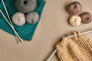 Grey and brown knitting wool and knitting on knitting needles on beige background. Top view. Copy space photo