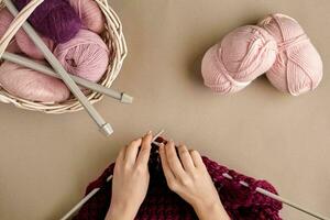 Close-up of female hands knitting wool sweater or plaid lilac color. Top view photo