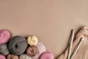 A group of colored balls of yarn and knitting needles on a beige background photo