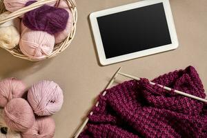 Balls of merino wool yarn, knitting on knitting needles on a beige surface. Top view photo