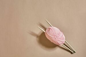 Pink knitting yarn ball and knitting needles top view photo