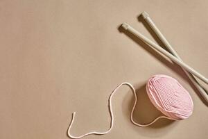 Pink knitting yarn ball and knitting needles top view photo