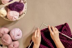 Close-up of female hands knitting wool sweater or plaid lilac color. Top view photo