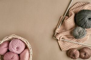 Balls of merino wool yarn, knitting on knitting needles on a beige surface. Top view photo