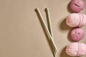 A group of colored balls of yarn and knitting needles on a beige background photo