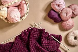 Balls of merino wool yarn, knitting on knitting needles on a beige surface. Top view photo