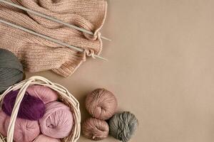 Balls of merino wool yarn, knitting on knitting needles on a beige surface. Top view photo