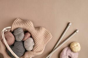 Different colored yarn in basket with knitting needles. Top view photo