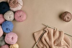 Set of colorful wool yarn and knitting on knitting needles on beige background. Top view photo