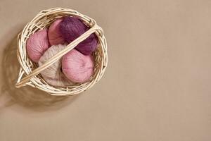 Pink coils of yarn in the basket on a beige background. Top view. Copy space photo