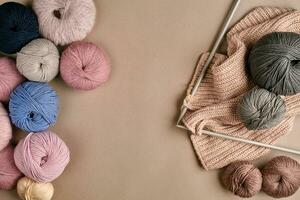 Set of colorful wool yarn and knitting on knitting needles on beige background. Top view photo