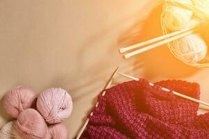 Balls of merino wool yarn, knitting on knitting needles on a beige surface. Top view. Sun flare photo