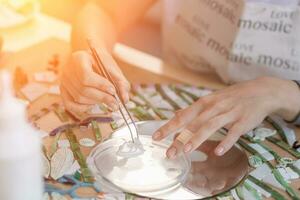 Hands of master working on new modern colorful mosaic. Close-up photo