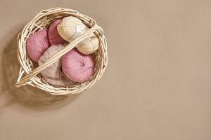 Pink coils of yarn in the basket on a beige background. Top view. Copy space photo