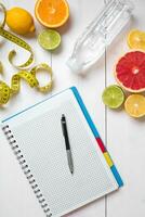 Healthy breakfast with fresh fruits and bottle of water with notebook on rustic wooden table. photo