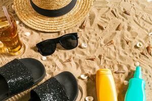 Summer beachwear, flip flops, hat, cold drink in a glass and seashells on sand beach. photo