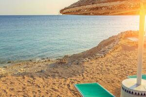 Sun umbrellas and empty deckchairs on the shore sand beach photo