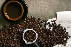 Coffee beans, sheet music and Coffee cup on a burlap background photo