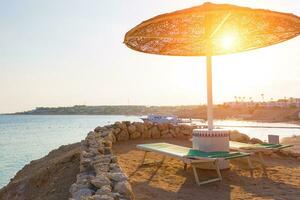 Umbrellas and empty deckchairs on the beach during sunset photo