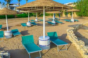 Sun umbrellas and empty deckchairs on the shore sand beach photo