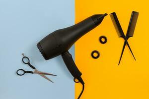 Styling hair with scissors, dryer and tools in barbershop on blue and yellow paper background top view mock-up photo