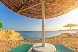 Umbrella and two empty deckchairs on the shore sand beach photo