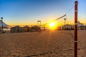 Sillhouette of a volleyball net and sunrise on the beach photo