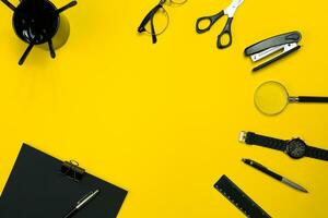 Black objects from the office on a yellow background. Work and creativity. Top view. photo