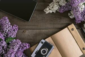 Lilac blossom on rustic wooden background with notebook for greeting message. Top view photo