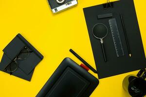 Black objects from the office on a yellow background. Work and creativity. Top view. photo