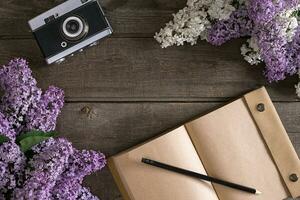 Lilac blossom on rustic wooden background with notebook for greeting message. Top view photo