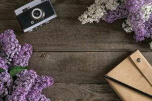 Lilac blossom on rustic wooden background with notebook for greeting message. Top view photo