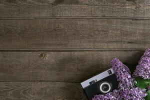 Lilac blossom on rustic wooden background with empty space for greeting message. Camera old. Top view photo