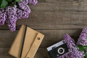 Lilac blossom on rustic wooden background with notebook for greeting message. Top view photo