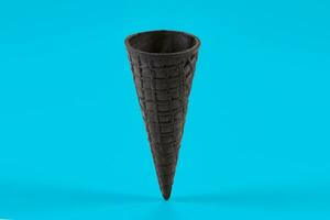 Empty, sweet black wafer cone for ice cream on blue background. Concept of food, treats. Mockup, template for your advertising and design. Close up photo