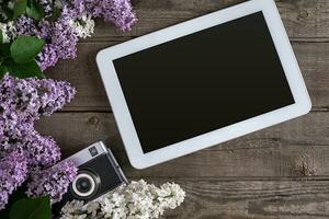 Lilac blossom on rustic wooden background, tablet with empty space for greeting message. Top view photo