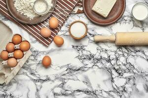 Close-up shot. Top view of a baking ingredients and kitchenware on the marble table background. photo