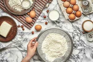 Close-up shot. Top view of a baker cook place, hands are working with a raw dough on the marble table background. photo