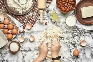 Close-up shot. Top view of a baker cook place, hands are working with a raw dough on the marble table background. photo